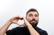 © Niko_Dali - A bearded man forms a heart shape with his hands against a white background, expressing love, affection, or care.