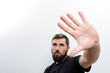 © Niko_Dali - A man with a beard extends his hand towards the camera against a plain white background, creating a sense of stopping or blocking.