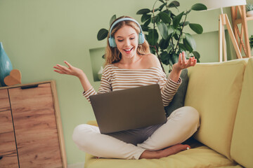 Wall Mural - Young woman enjoying a relaxing weekend at home listening to music while sitting in a casual living room setting