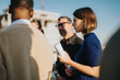 © qunica.com - A multicultural group of business people gathers on a high tower balcony, discussing ideas and collaborating as the sun sets. The scene captures teamwork and diversity in an outdoor urban setting.