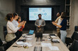 © qunica.com - A team of business people applaud a successful presentation during a late-night meeting in the office. The group is gathered around a conference table with laptops and documents, celebrating their