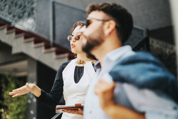 Wall Mural - Two business people engage in a lively discussion outside an urban office building, emphasizing collaboration and contemporary style.