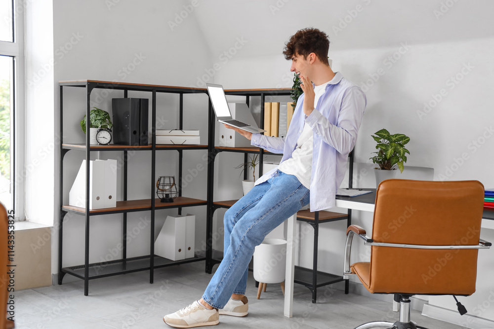 Young man video chatting with laptop in office