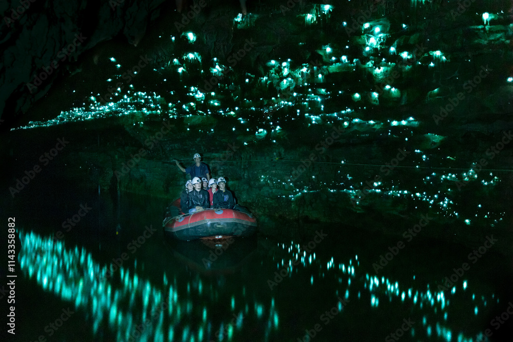 People on a raft visiting a glowworm cave illuminated by bioluminescent ...