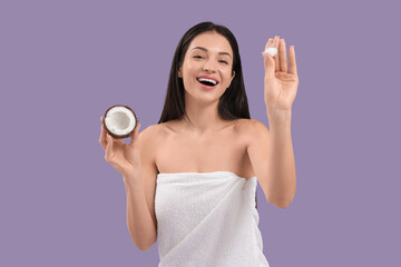 Wall Mural - Beautiful young happy woman with coconut and cream on purple background