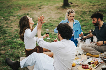 Poster - A group of multiracial friends enjoys a relaxing picnic on a cloudy day in a scenic outdoor location, sharing laughter and wine. The atmosphere is filled with joy and togetherness.