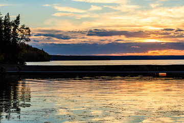 Wall Mural - The sky is a beautiful orange color as the sun sets over the water