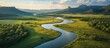 © gufron - Aerial view of a winding river flowing through a lush green valley with mountains in the background.