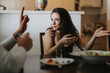 © qunica.com - A woman passionately discusses a topic at the dinner table, using hand gestures to emphasize her point. The setting is cozy, highlighting a moment of connection and interaction.