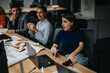 © qunica.com - A diverse group of colleagues collaborating in a modern office setting, focused on project brainstorming. They are engaged in a lively discussion, working together and strategizing to meet deadlines.