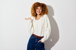 © SHOTPRIME STUDIO - Cheerful young woman with curly hair in a cozy white sweater posing against a light background, showcasing a joyful expression and playful gesture, ideal for lifestyle content