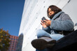 © Johnér - Low angle view of mid adult woman using mobile phone while sitting outside building