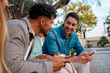 © Cavan Images - Friends enjoying time together while using smartphones in a park