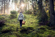 © Johnér - Rear view of woman carrying basket on field in forest