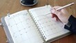 © 晓日 陈 - Event planner timetable agenda plan on year 2024 schedule event. Business woman checking planner on mobile phone, taking note on calendar desk on office table. Calendar event plan, work planning