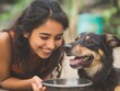 © somchai20162516 - A young woman smiling while feeding her pet dog, showing affection and care.