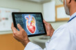 © romanets_v - Mature hispanic male doctor examining digital heart model on tablet in medical setting