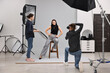 © New Africa - Photographer and assistant working with model in professional photo studio