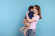 © New Africa - Happy mother with her cute little son on light blue background, space for text