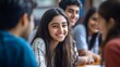 © Nathan - A cheerful South Asian teenage girl smiles during a lively group discussion with friends, showcasing youth and connection.