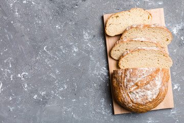 Wall Mural - Freshly baked bread slices on cutting board against white wooden background. top view Sliced bread