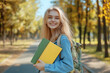 © Inspire Shots Hub - Teenage girl enjoys a sunny day in the park while carrying books and smiling