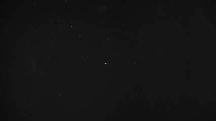 Dust particles abstract bokeh, white particles floating in the air on black background in slow motion, 4k