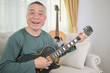 © Wosunan - Senior man a veteran guitarist plays the old electric guitar at home