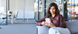 © Stock 4 You - Young dreaming Indian business woman manager ceo using cell phone mobile app. Pondering Latin Hispanic female businesswoman holding smartphone in office for trading, work online, Banner, copy space