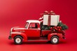 © Mimi - A Christmas-themed red truck carrying a large gift box wrapped in red ribbon on a seamless red background