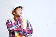 © SAISUPAWKA - An Asian male engineer standing outside inspecting work and talking on the phone giving instructions.