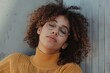 © darshika - Content adult overweight female in eyewear curly hair against ribbed wall in daytime