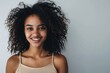 © darshika - Smiling African woman with curly hair on grey background.