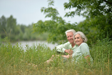 Canvas Print - Portrait of senior couple sitting on the grass in the park