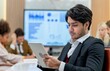 © BESTIMAGE - A man in a suit is sitting in a conference room looking at a tablet.