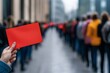 © Star - A person holding a red card in a crowd, symbolizing protest or action.