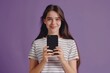 © darshika - Beautiful young woman in striped shirt holding smartphone with black screen.