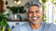 © mashimara - A middle-aged man with silver hair smiles warmly in a bright, green indoor space, representing happiness, health, and positivity.