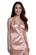 © Flash - A young woman with long brown hair smiles in a pink satin dress, standing against a white background.