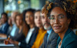 © Vadim - A woman with glasses is smiling at the camera in front of a group of people. Concept of unity and camaraderie among the group, as they all appear to be working together or attending a meeting