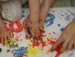 © Dilya - Mom plays with children, funny baby shows his palms painted with paint. Creative art classes. Laughter. Happy children and mom finger painting on paper at home. Bright colors, gouache and watercolors