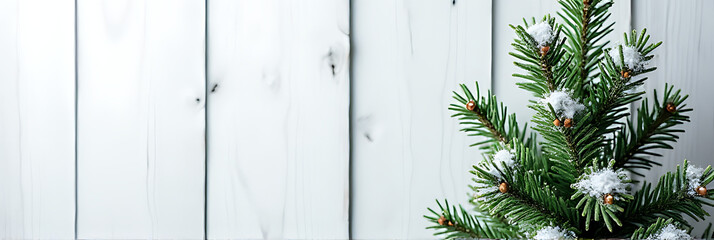 Wall Mural - a christmas fir tree decorated with a pine branch and placed against a snowy white wooden backdrop._