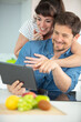 © auremar - happy couple in home kitchen using electronic tablet