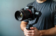 © miss irine - Male videographer holds modern dslr camera on 3-axis gimbal. Professional videographer uses advanced tech equipment. Creative hobby, work concept. Modern tech equipment. Man working with camera,