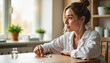 © Nataly - Woman sitting thoughtfully at kitchen table with pills.