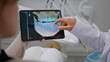 © stockbusters - Dentist hands holding x-ray on tablet at consultation stomatology clinic closeup