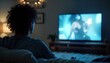 © miss irine - Person engrossed in TV program. Person sits on couch in home. Watching vivid screen. Night time. Media influence. Entertainment overload. Digital addiction.