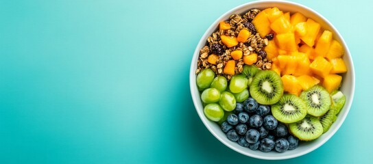 Wall Mural - Colorful fruit and granola bowl on turquoise background.