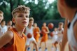 © LifeMedia - A young athlete in an orange jersey intensely participates in a basketball drill, surrounded by teammates, representing sportsmanship, focus, and youthful energy.