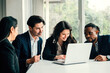 © sorapop - In a meeting room, diverse group of happy businesspeople, both men and women, collaborates on laptop. teamwork diversity and togetherness are evident as they discuss, plan, and strategize success.